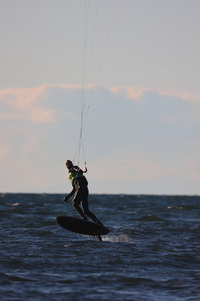 A kite surfer skillfully navigates the waves in Vancouver, capturing the thrill of water sports against a sunset backdrop.